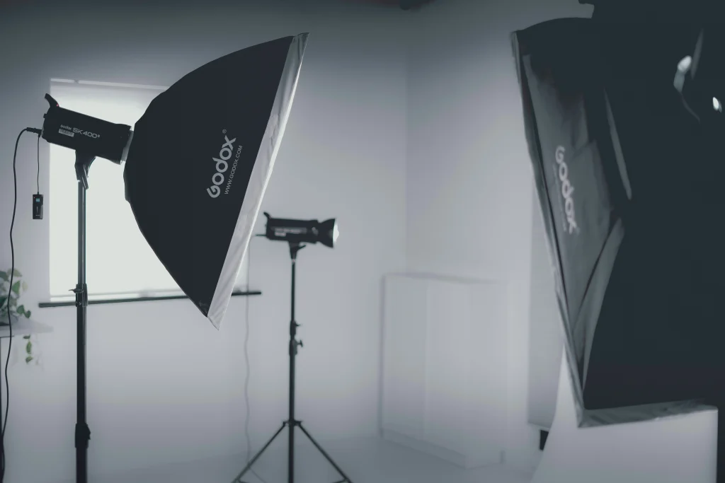 A photography studio setup with two large lights, a smaller studio light on stands, and sleek commercial LED boards.