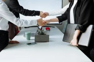Business people shaking hands and agreeing to a deal over a table.