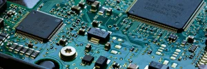 Close-up of a green printed circuit board featuring various electronic components and gold circuit traces, often used in box build assembly and turnkey solutions for streamlined electronics manufacturing.